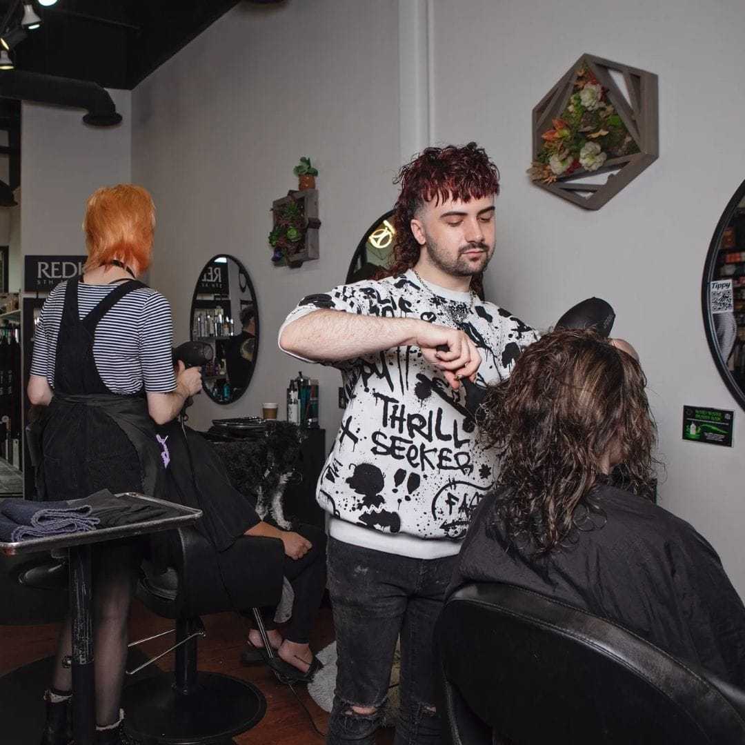 Stylists working on customers' haircuts in a trendy salon.
